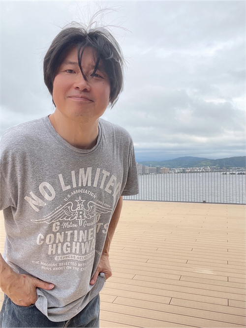 松江市役所6階展望デッキで宍道湖を背景に立つ松江観光大使斉藤浩